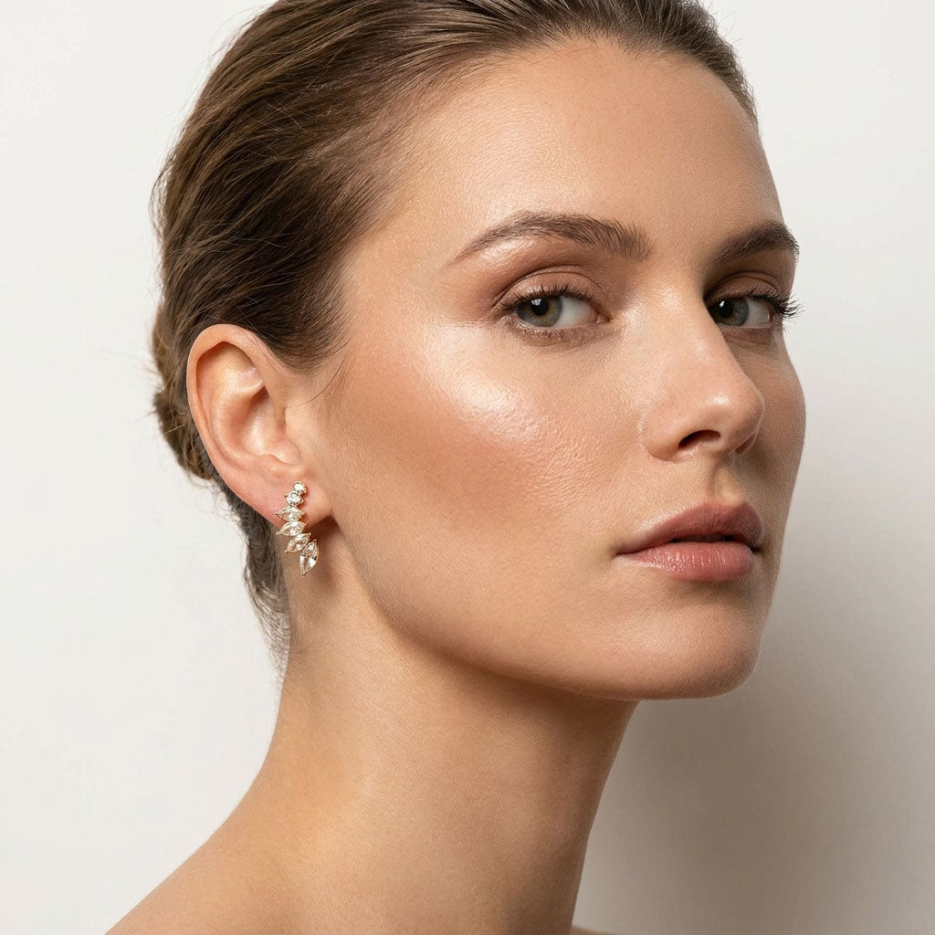 Model wearing gold-plated leaf earrings with sparkling cubic zirconia in a bright studio