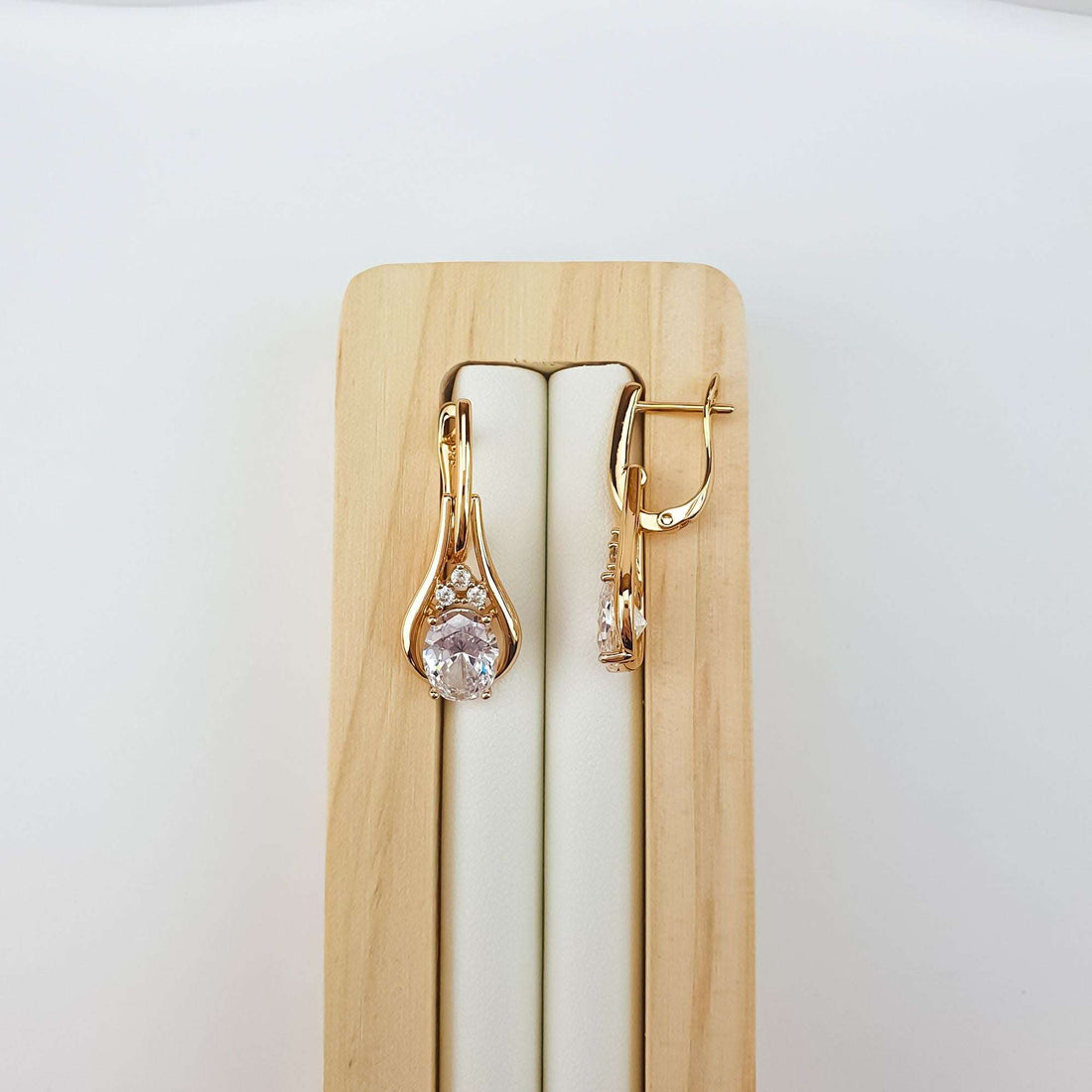 Cubic zirconia earrings on a wooden stand, curved clasp and shiny gold plating
