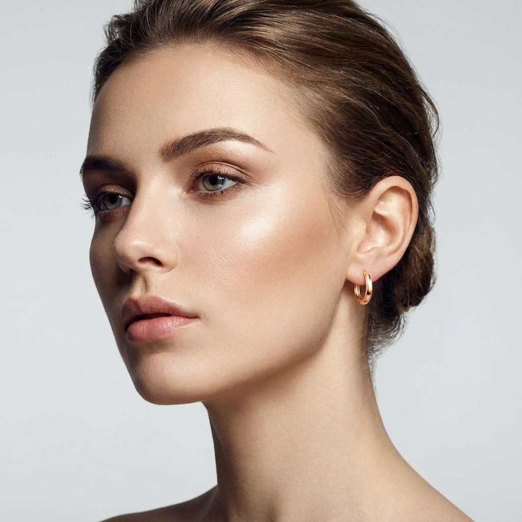 Model wearing a gold-plated hoop earring, smooth shiny shape in close-up