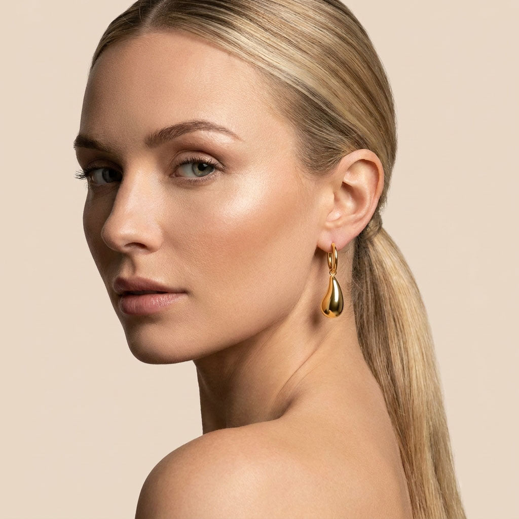 Model wearing gold-plated hoop earrings with a smooth teardrop drop
