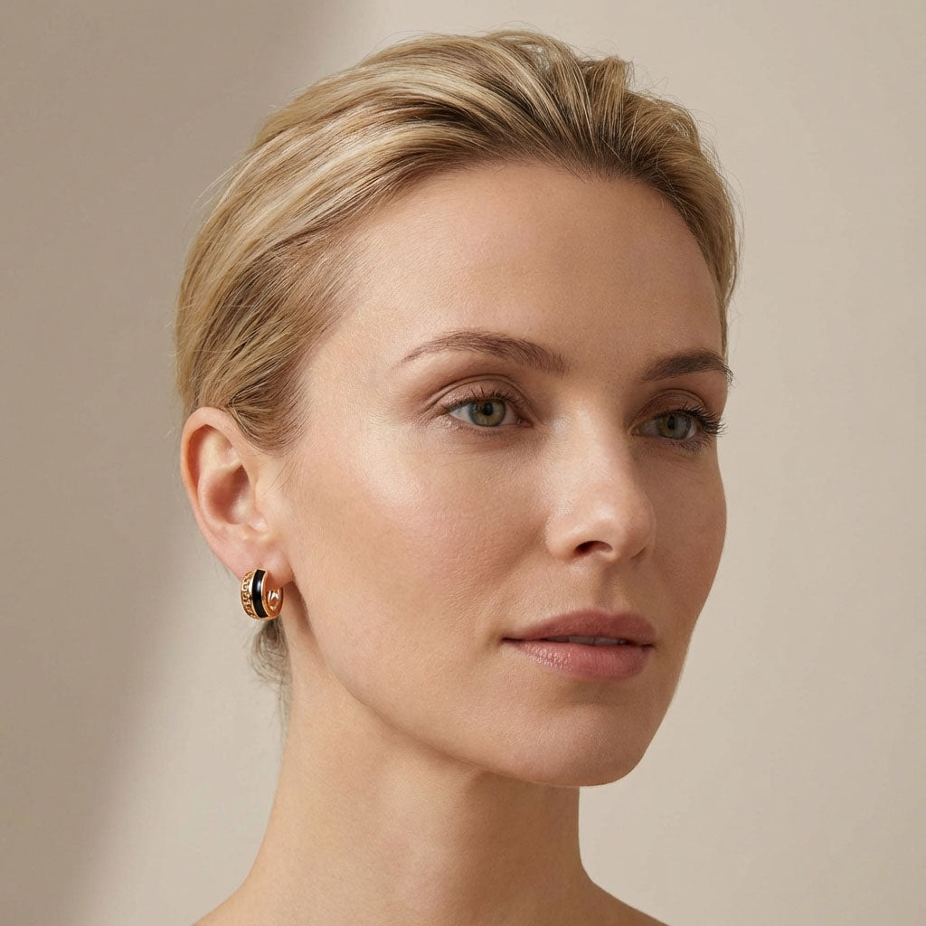 Model wearing a gold-plated hoop with a black enamel band and cut-outs