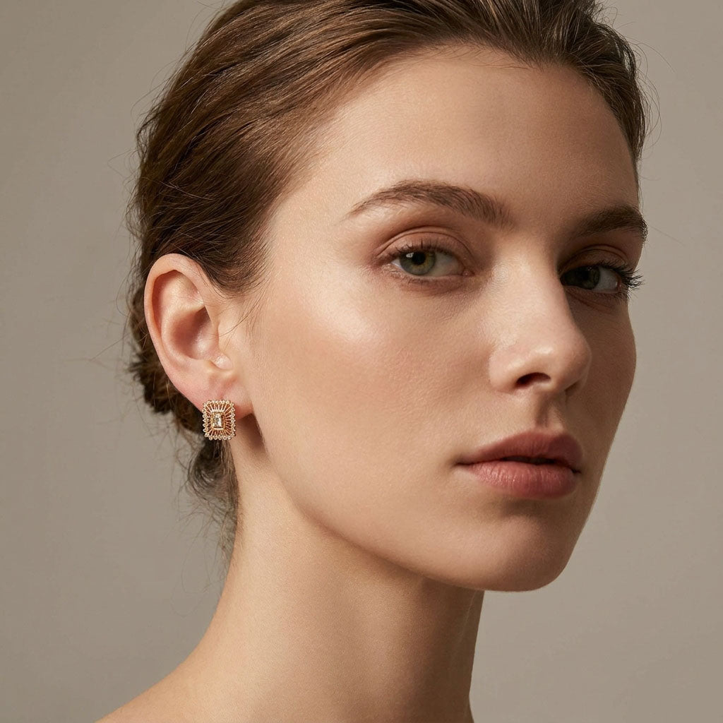 Model wearing rectangular gold-plated earrings with a clear cubic zirconia