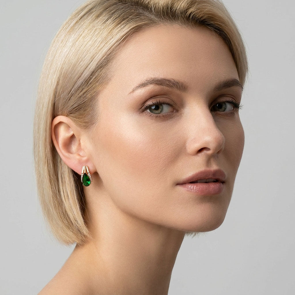 Blonde model wearing a gold-plated earring with a bright green teardrop stone