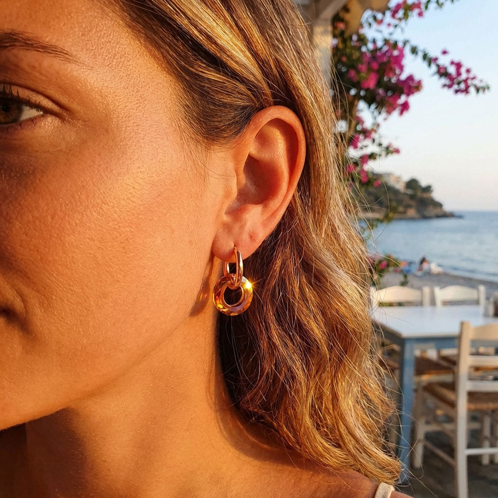 Model wearing hoop earrings with an orange crystal ring in sunset light