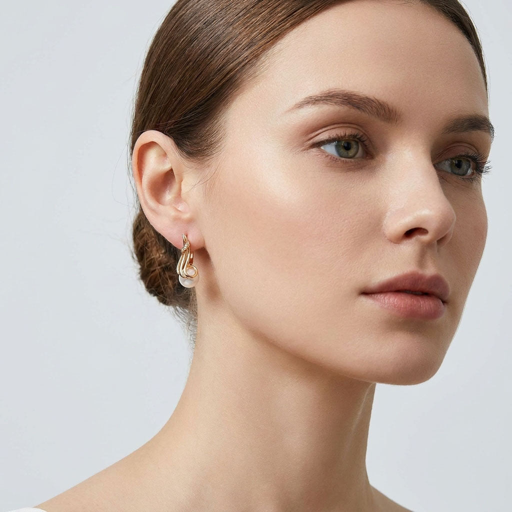 Model wearing a gold-plated earring with a white pearl, close-up at the ear