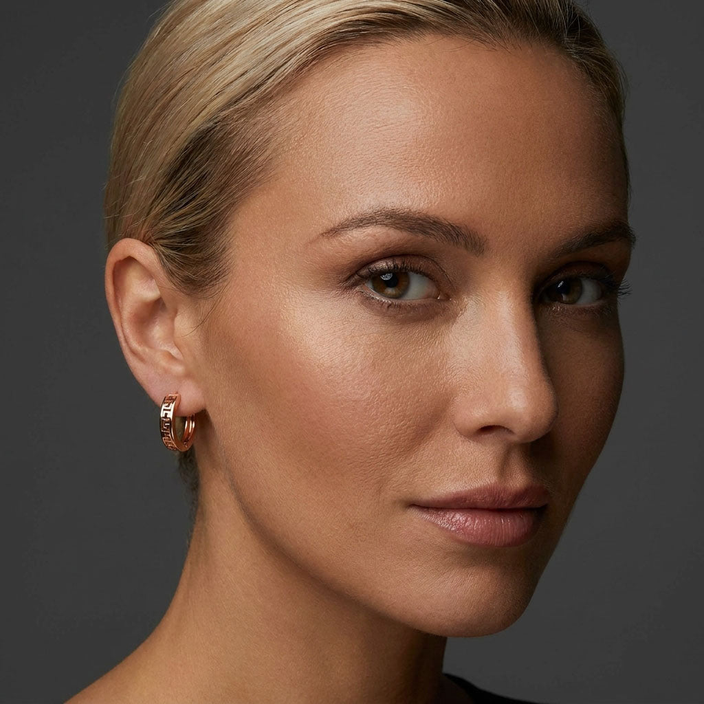 Close-up of a meander hoop earring on a model's ear against dark grey