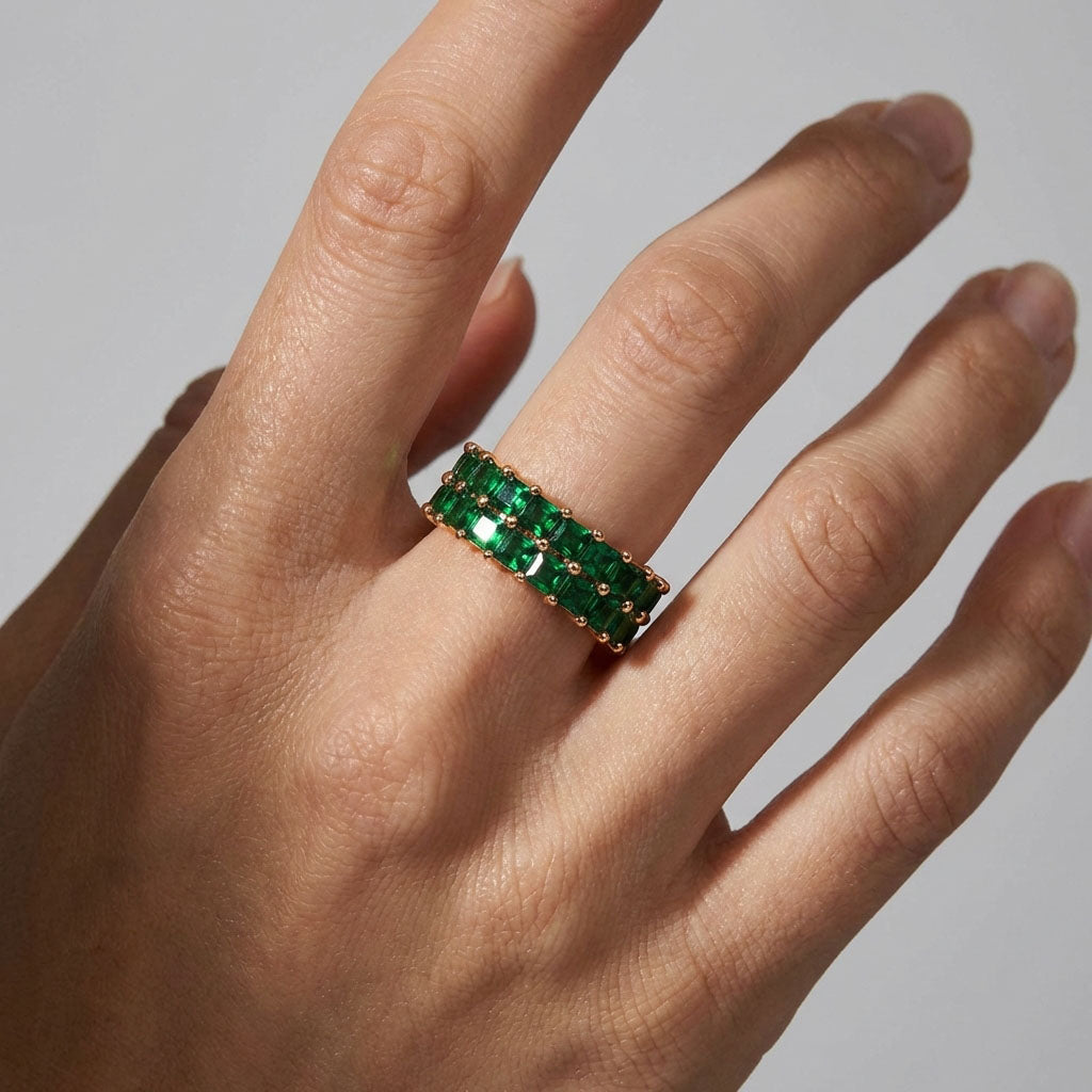 Gold-plated ring with two rows of bright green crystals on a woman's finger