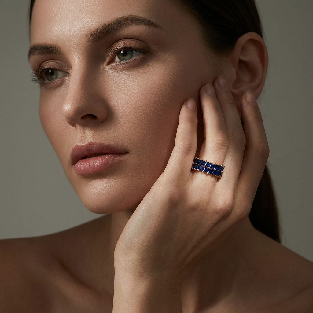 Model holding her hand to her cheek, wearing a gold-plated dark blue crystal ring