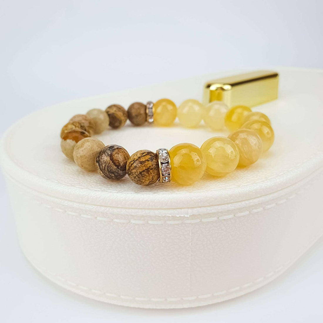 Natural stone bracelet on a white gift box, close up of gold-tone crystal spacers