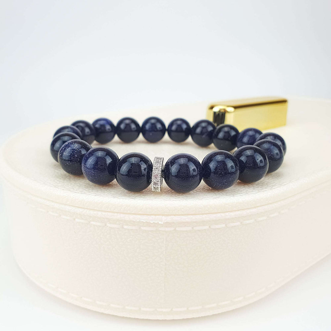 Blue goldstone bracelet side view on a pale gift box with a sparkling spacer