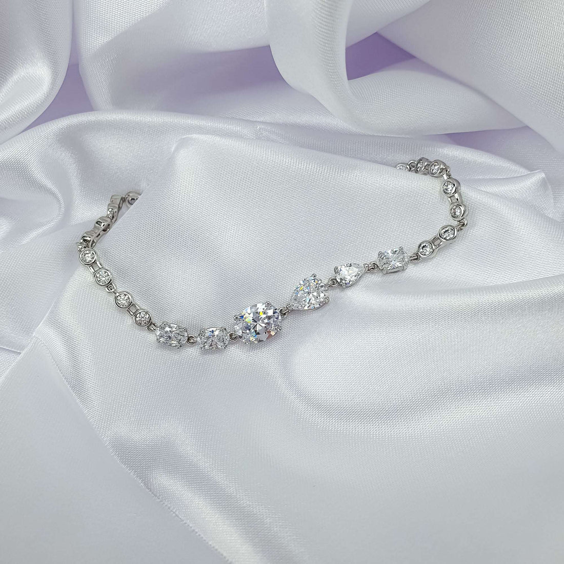 Silver-tone bracelet with a row of cubic zirconia and teardrop stones on satin