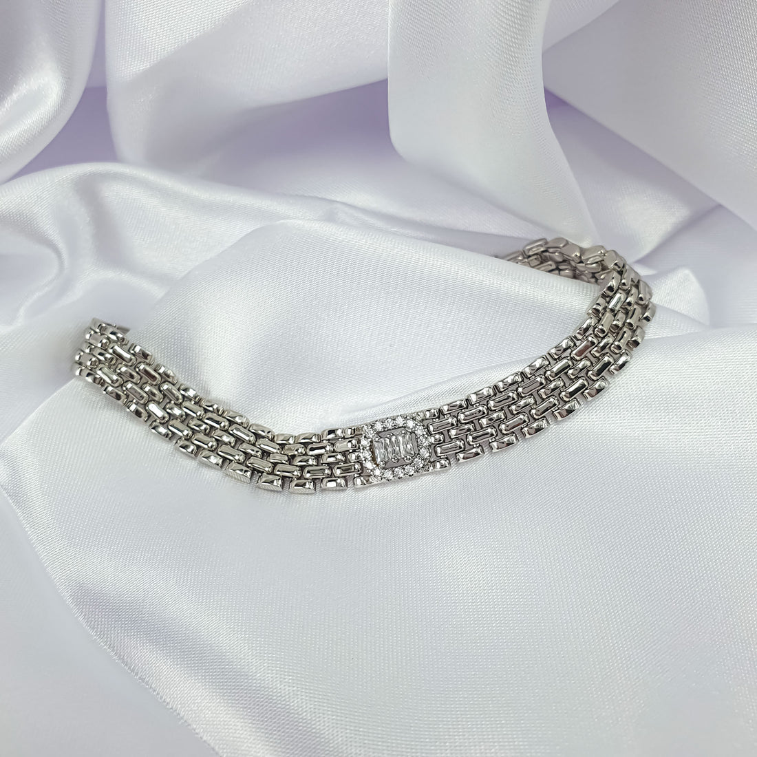 Silver-tone bracelet with a halo-set rectangular stone on white satin