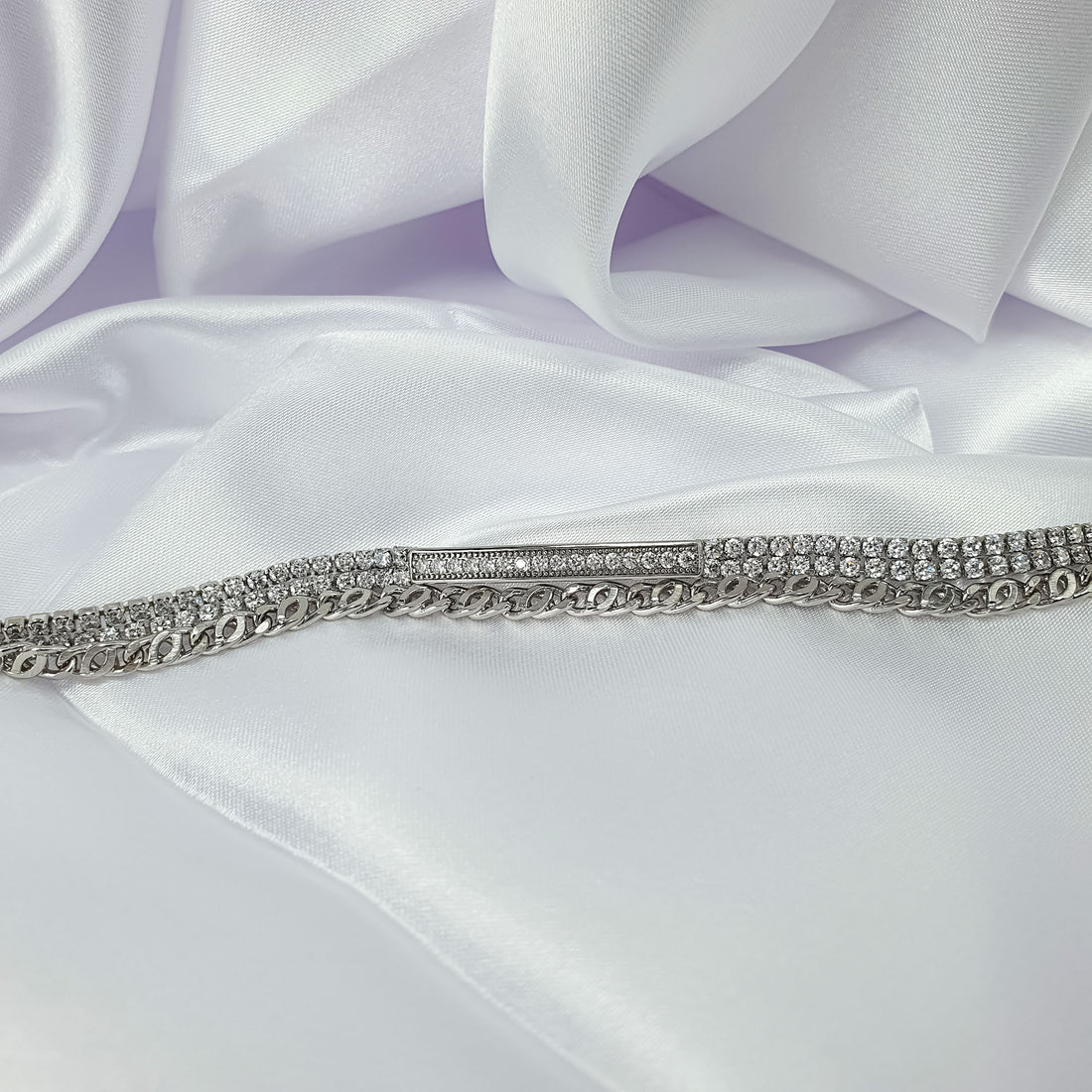 Sparkling cubic zirconia bracelet with chain links and a stone band on white satin