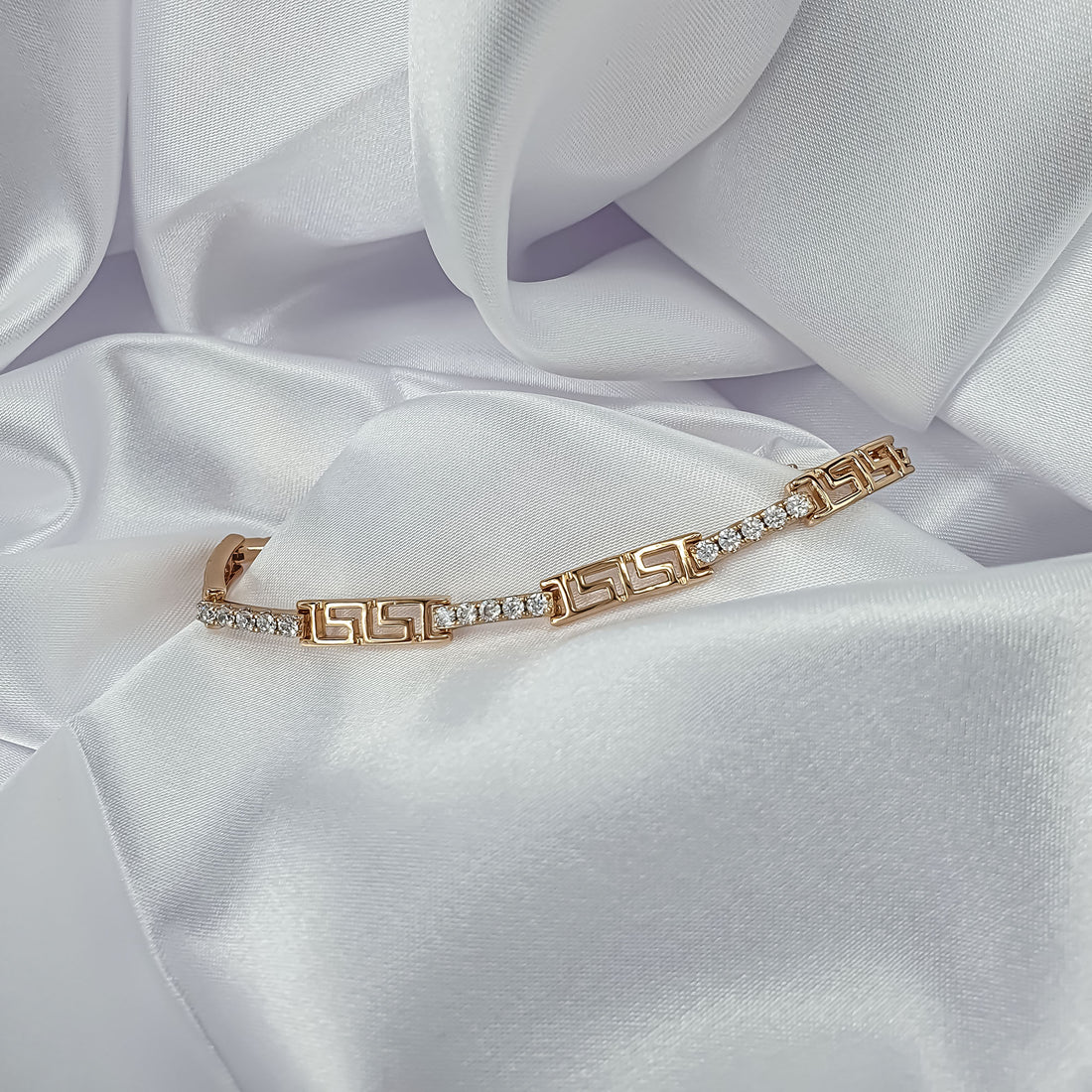 Narrow gold-plated bracelet with Greek meander pattern and clear cubic zirconia on satin