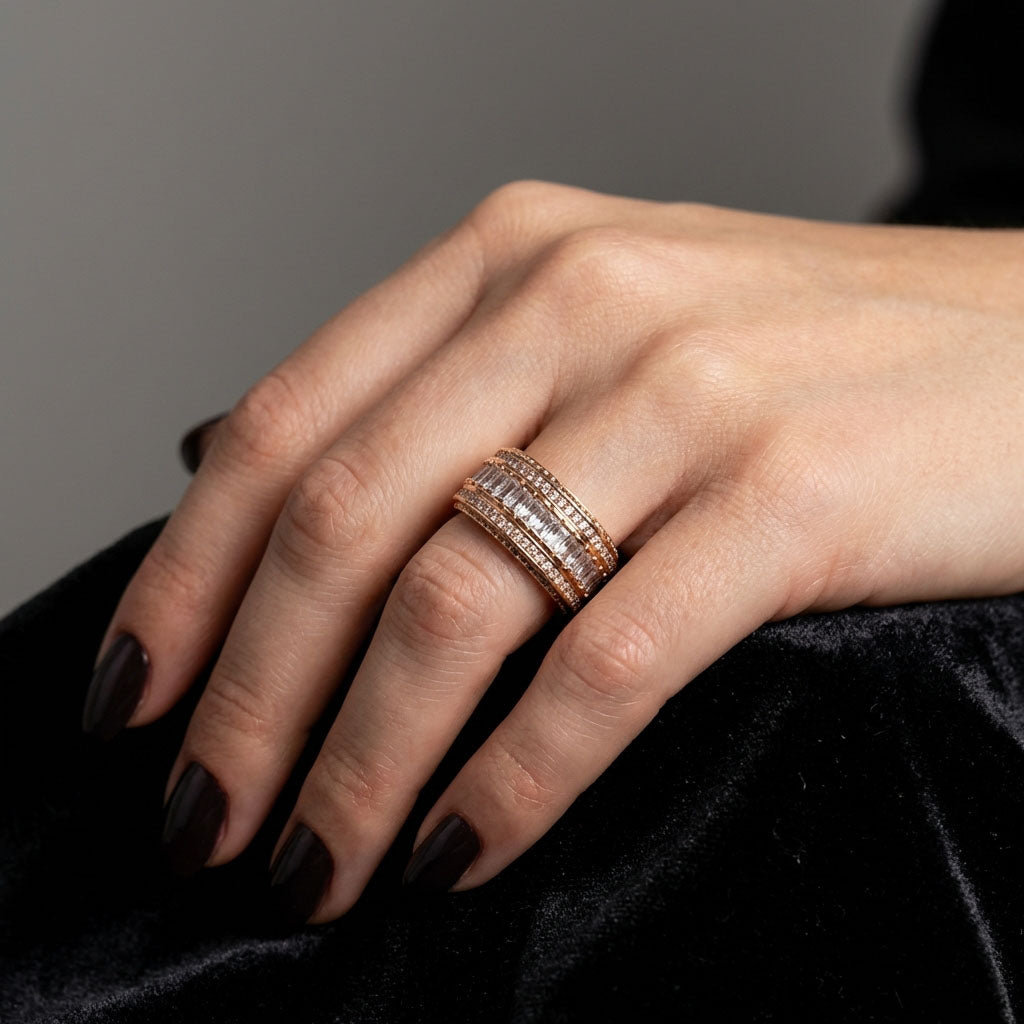 Wide cubic zirconia ring on a model's finger against black velvet, dark manicure