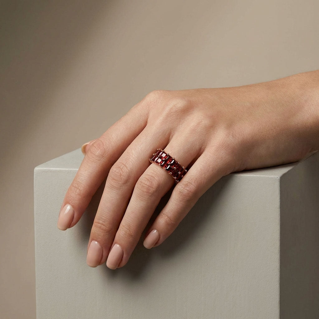 Model's hand resting on a light cube, wearing a wide red cubic zirconia ring