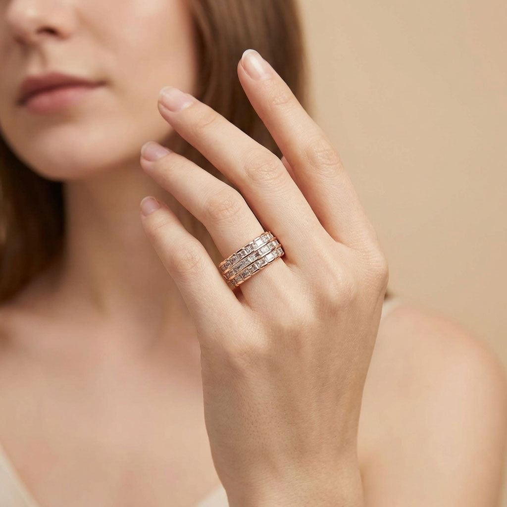 Model's hand wearing a wide gold-tone ring with three rows of sparkling stones