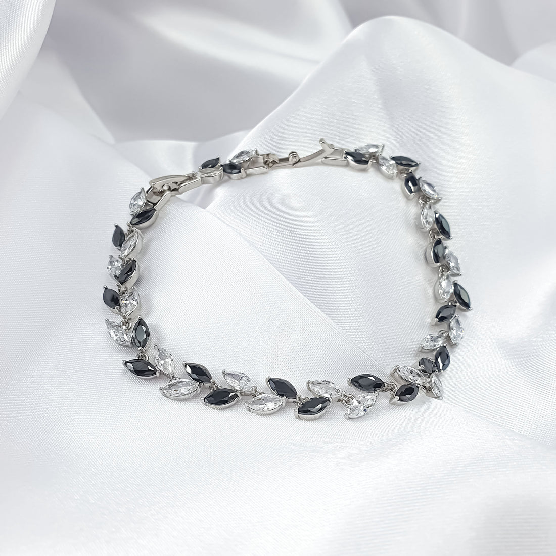 Silver-tone bracelet with a row of black and clear leaves on silk