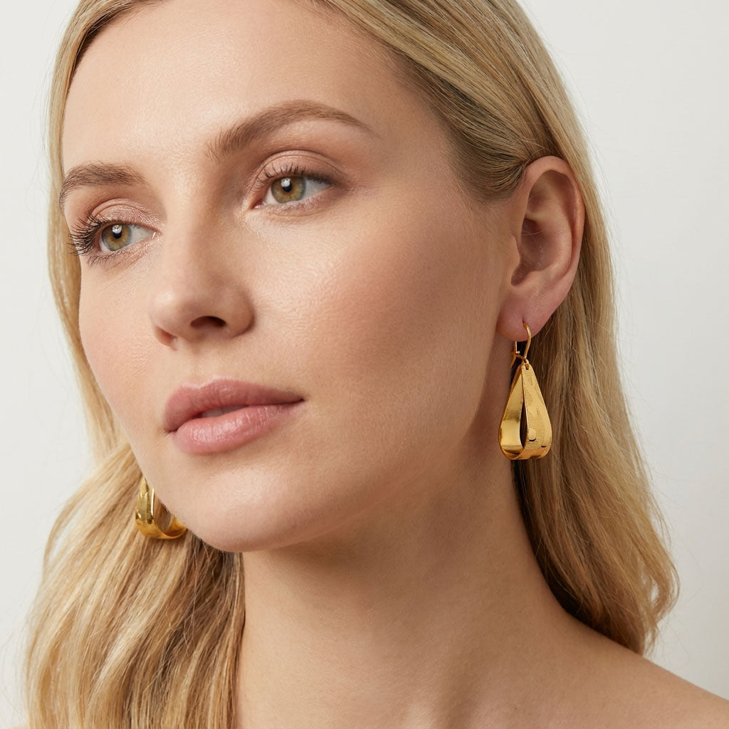 Model wearing long twisted gold-plated earrings with a glossy surface