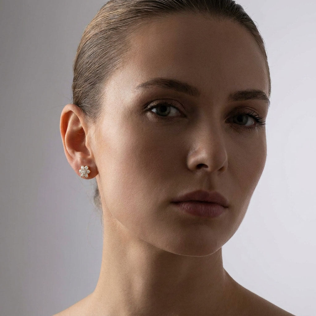Model wearing a gold-plated flower stud with white cubic zirconia, close-up portrait