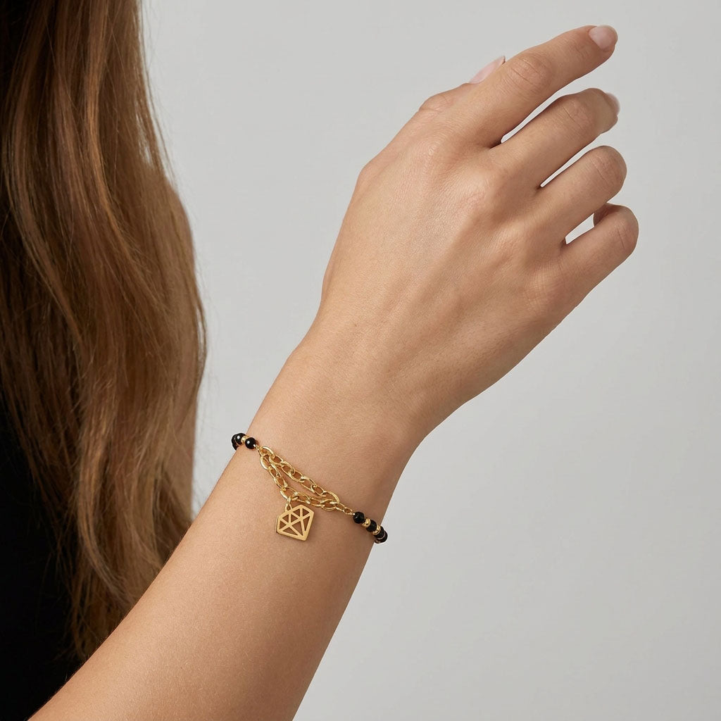 Black bead bracelet with a diamond-shaped charm on a model's wrist, light background