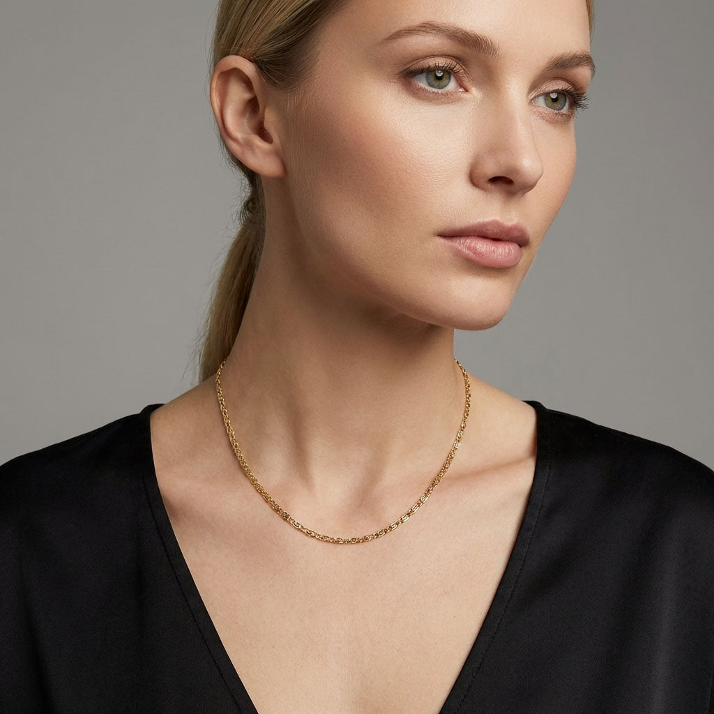 Fine gold-plated chain on a model's neck, worn with a black low-cut blouse