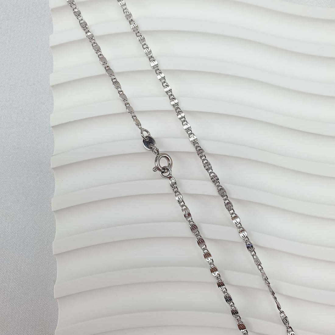 Close-up of a platinum-tone bird's eye chain and secure ring clasp