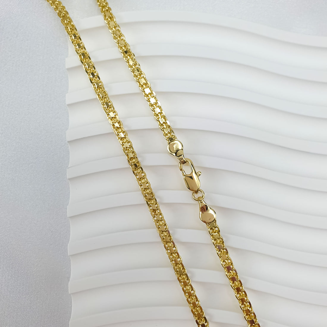 Gold-tone Bismarck chain on a light wavy base, dense link texture visible