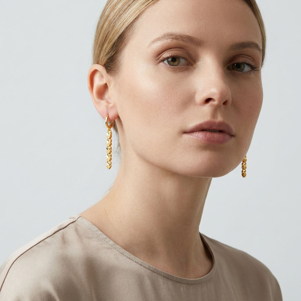 Model wearing long gold-plated heart earrings that swing along the neck