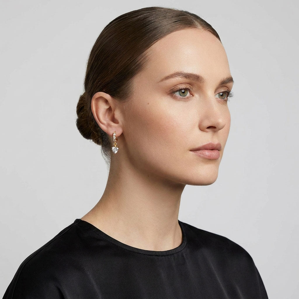 Model in a black blouse wearing gold-plated heart earrings with a zirconia drop