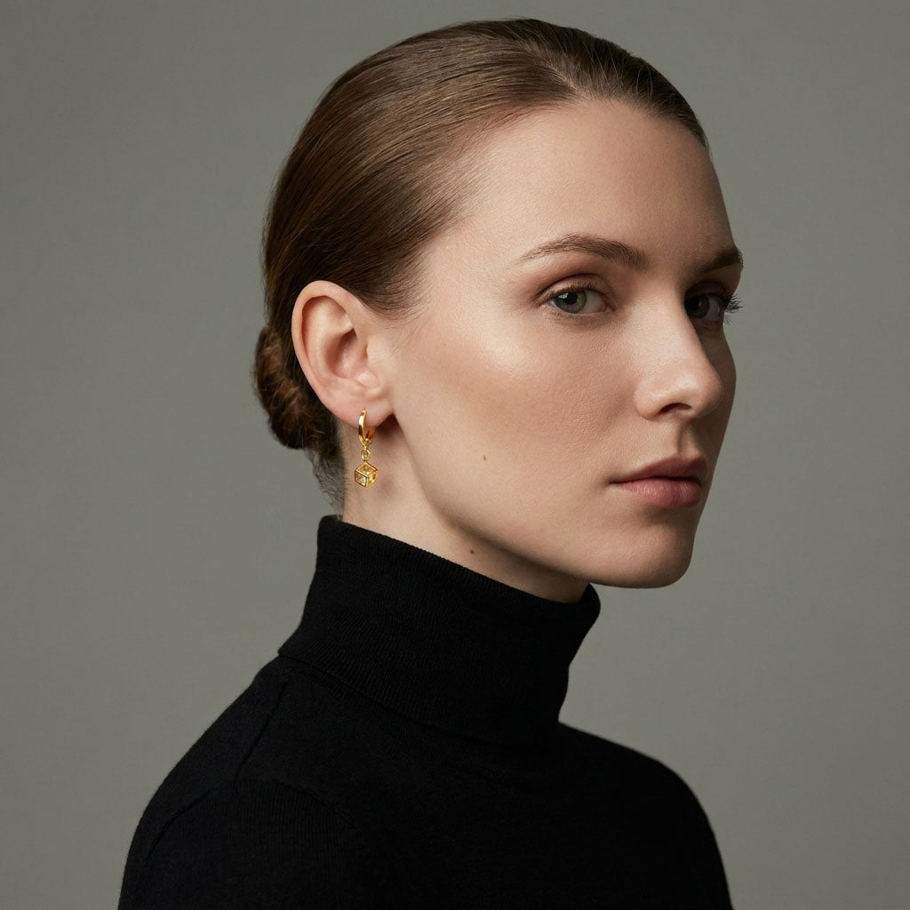 Model in a black jumper wearing a gold-plated hoop with a cube charm