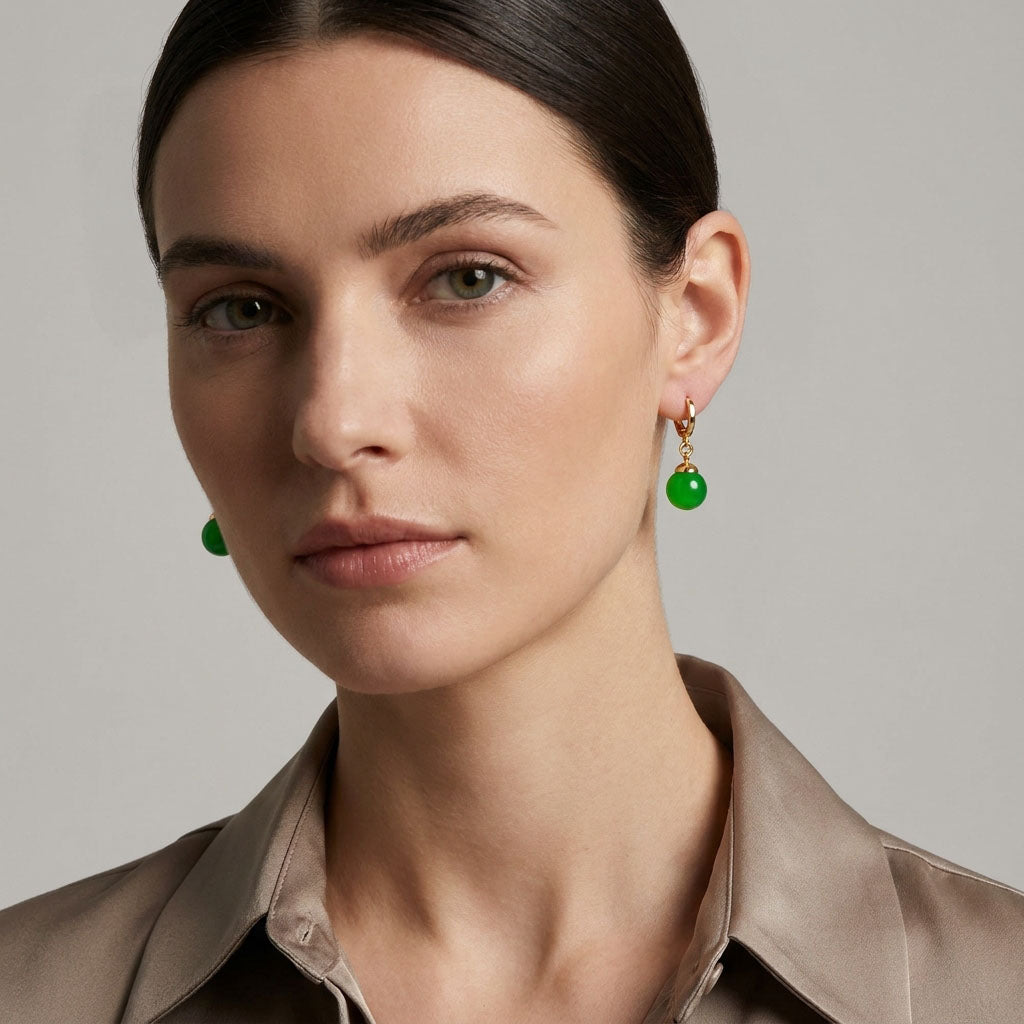 Model in a beige satin shirt wearing a green bead earring