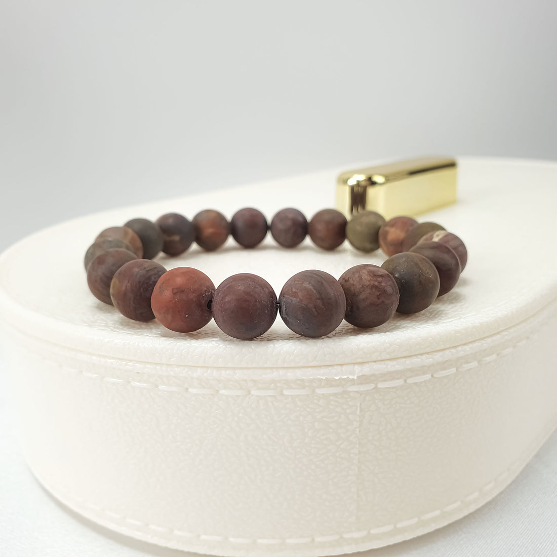 Agate bead bracelet on a white jewellery box, warm rust tones