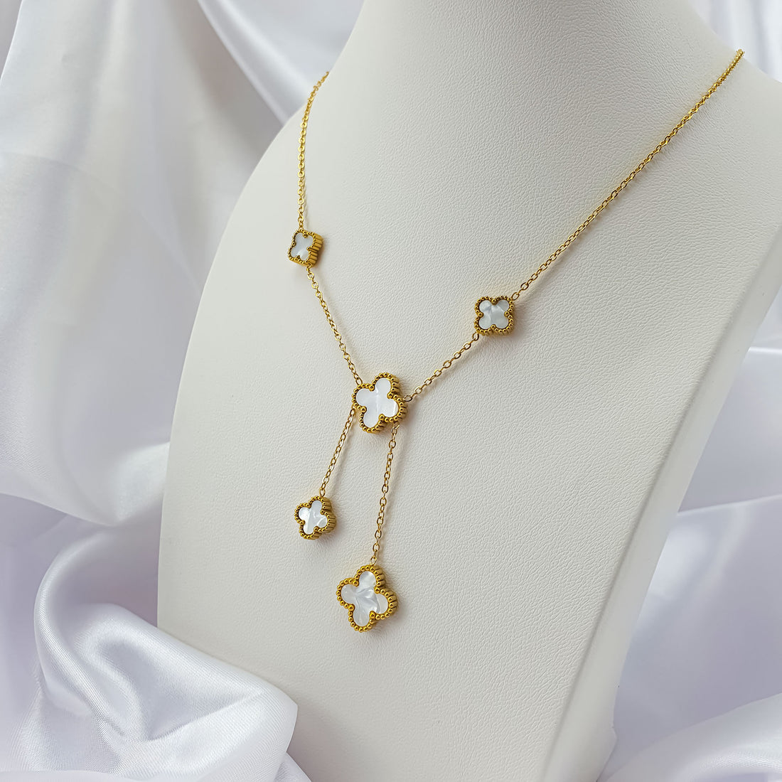 White clover necklace on a stand with two drops hanging down