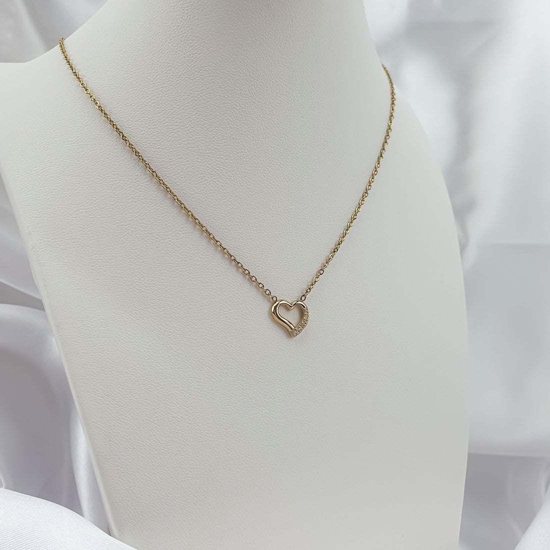 Gold-plated heart necklace displayed on a white bust
