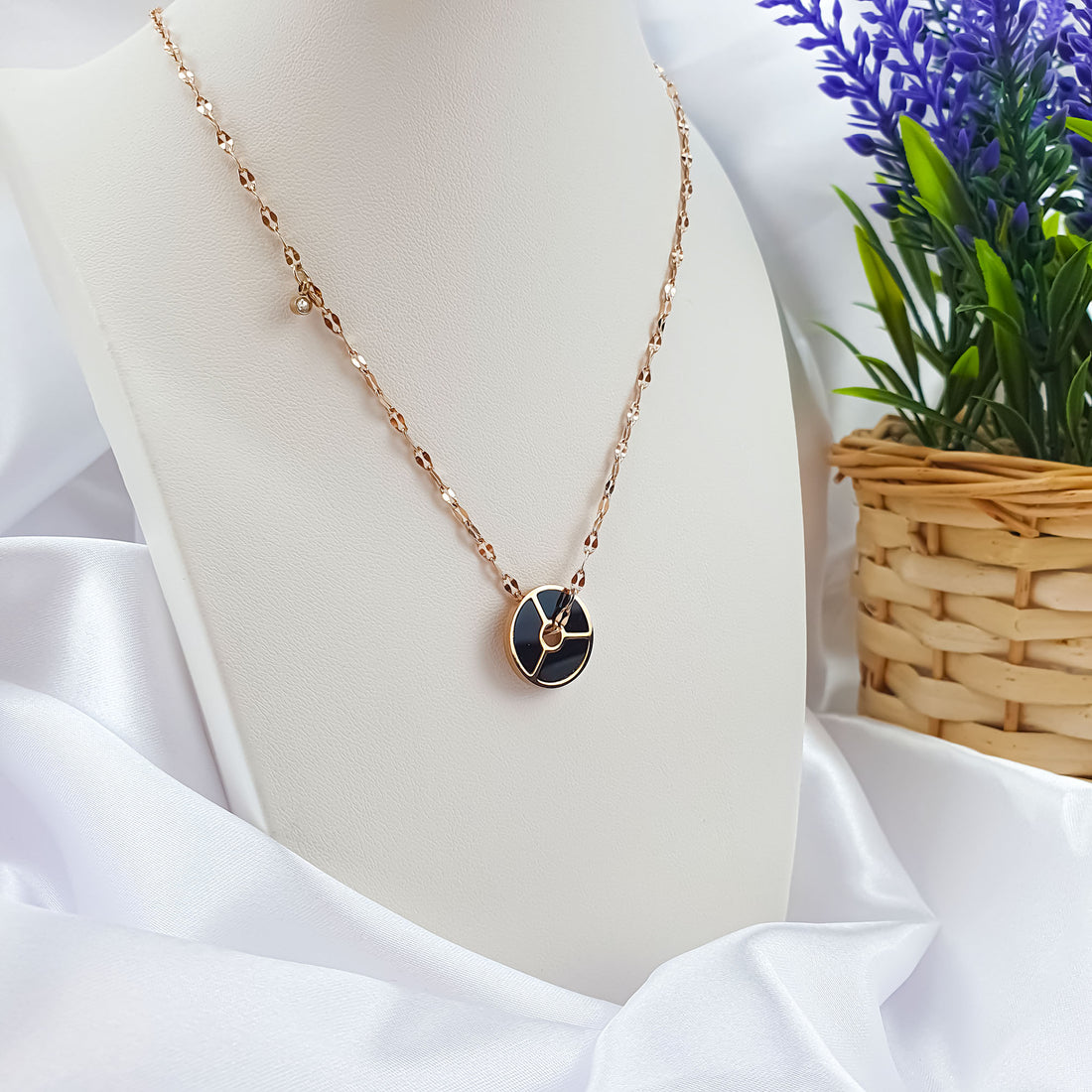 Black circle necklace on a white bust with a lavender sprig beside it