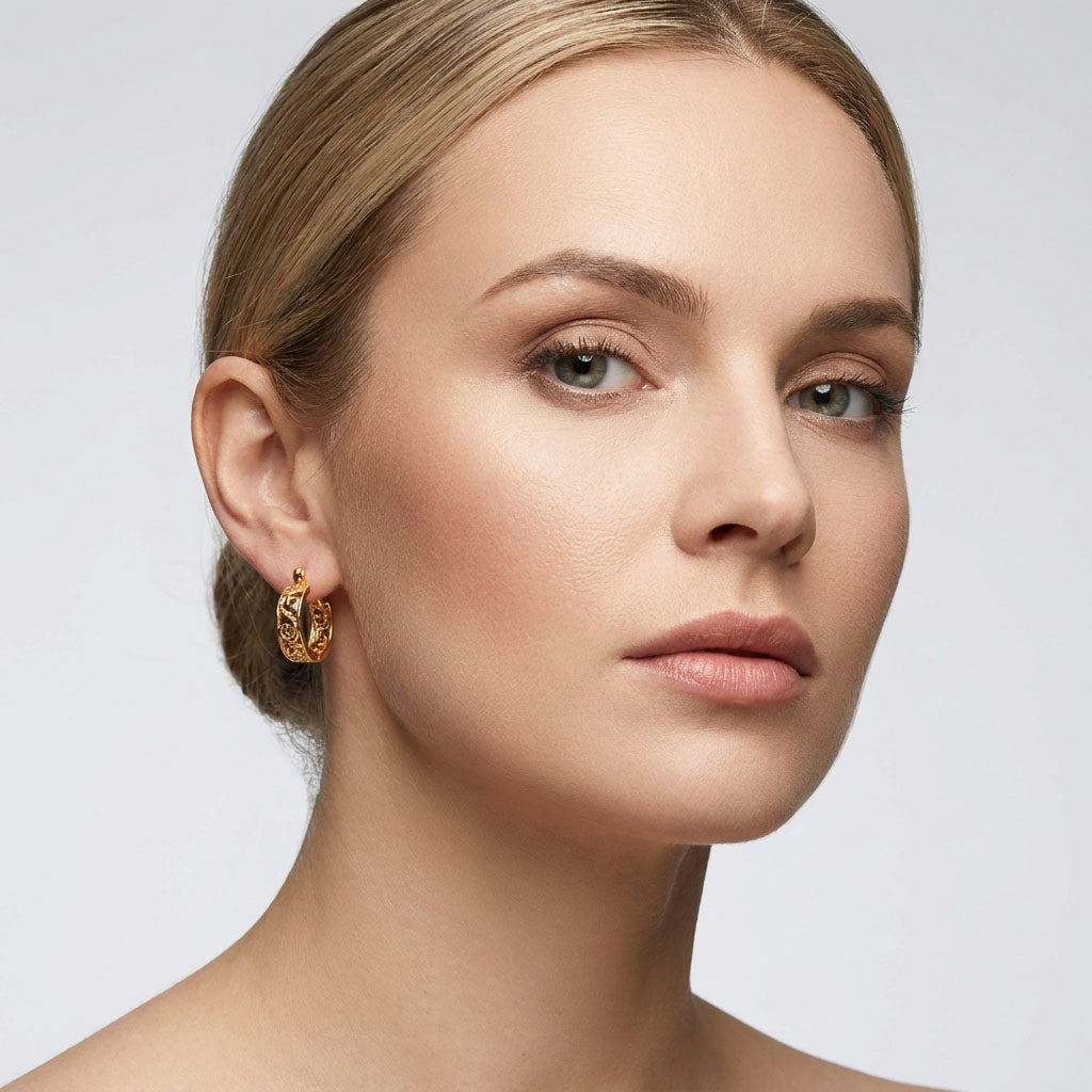 Model wearing round openwork earrings, the scrolls standing out by her ear