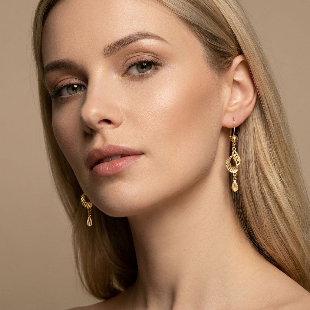 Model wearing long teardrop earrings, the gold-plated drop hanging by her face