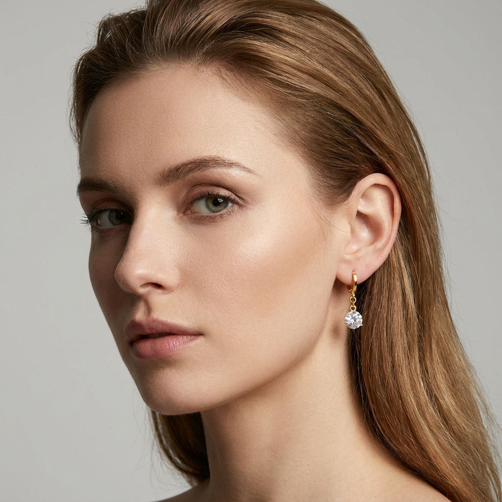 Fair-haired model wearing a gold-plated earring with a sparkling white stone