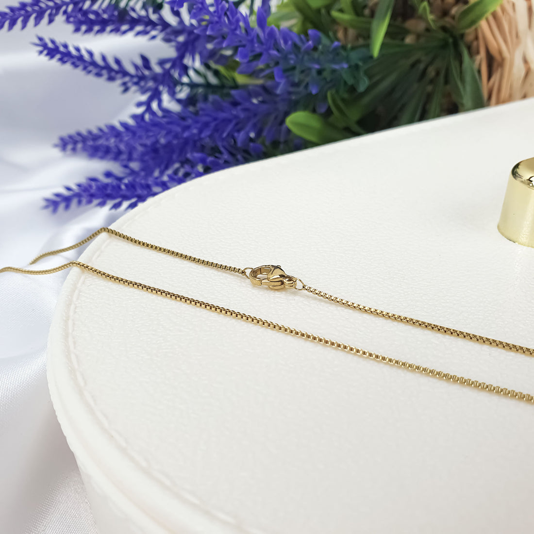 Delicate gold-tone Venetian chain with a lobster clasp on a light surface