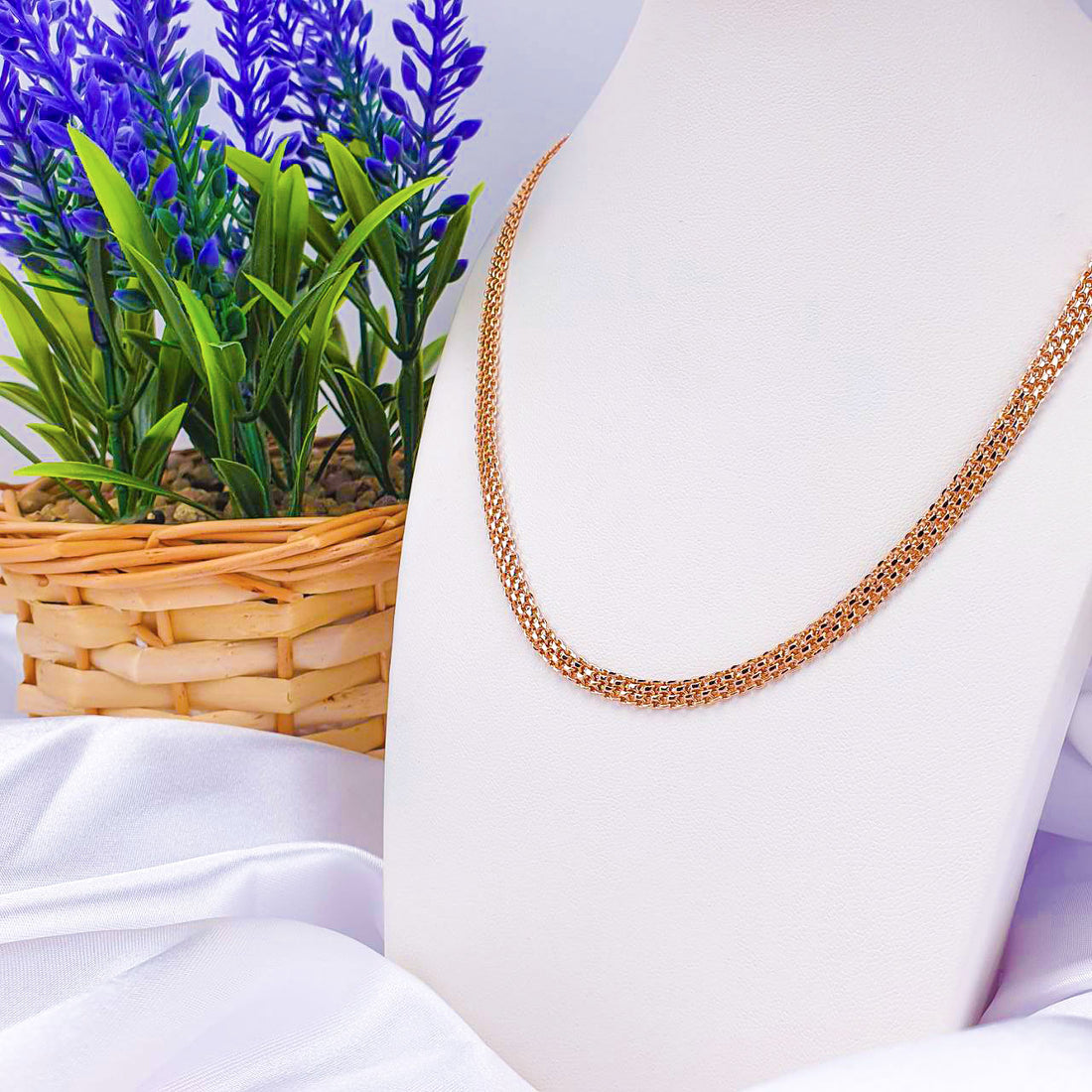 Fine gold-plated Bismarck chain on a white bust beside a bunch of lavender