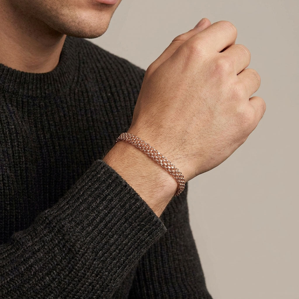 Gold-plated Bismarck bracelet on a man's wrist against a dark knitted jumper