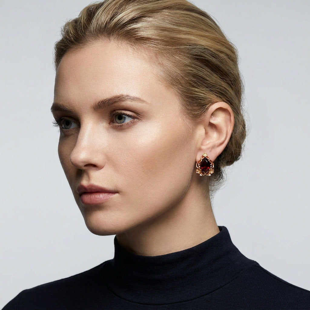 Model in a black roll-neck wearing gold-plated earrings with a red teardrop