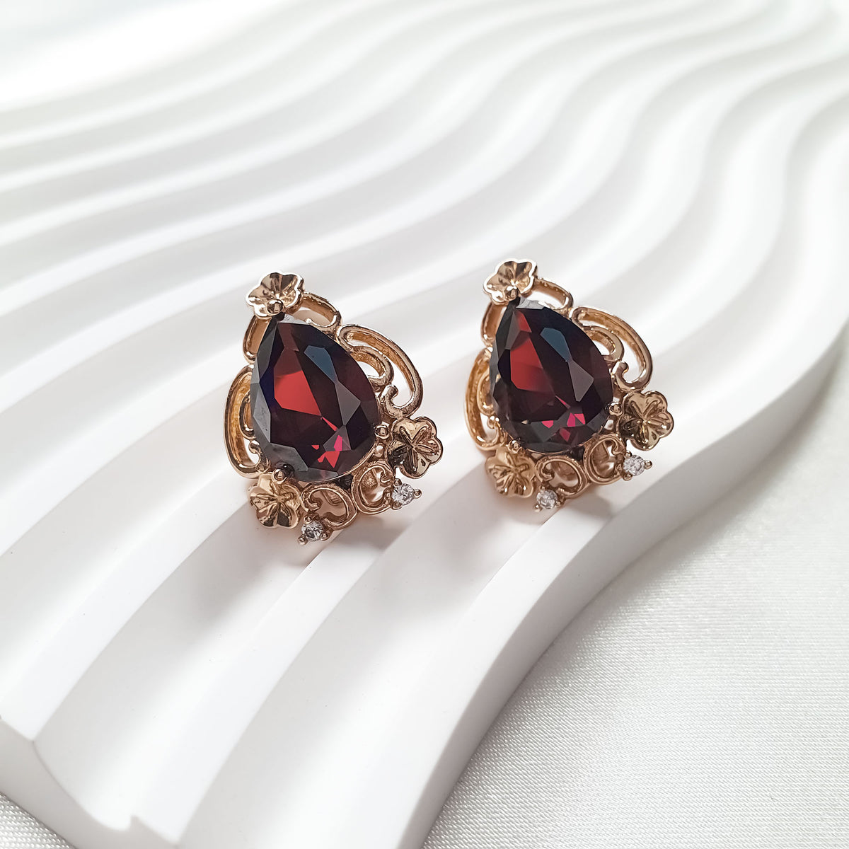 Pair of earrings with dark red teardrops in openwork frames and small stones