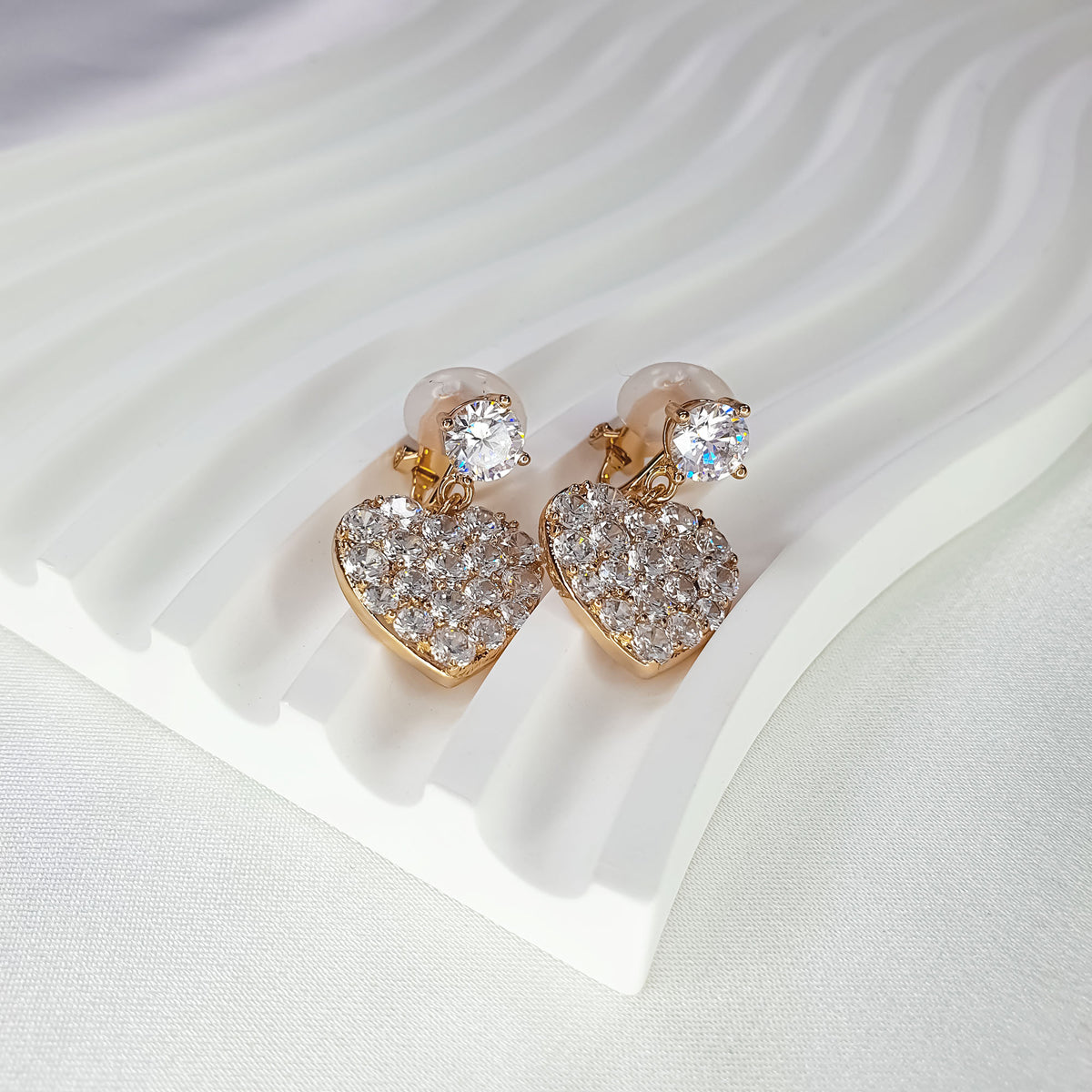 Close-up of heart earrings with sparkling cubic zirconia on a white stand