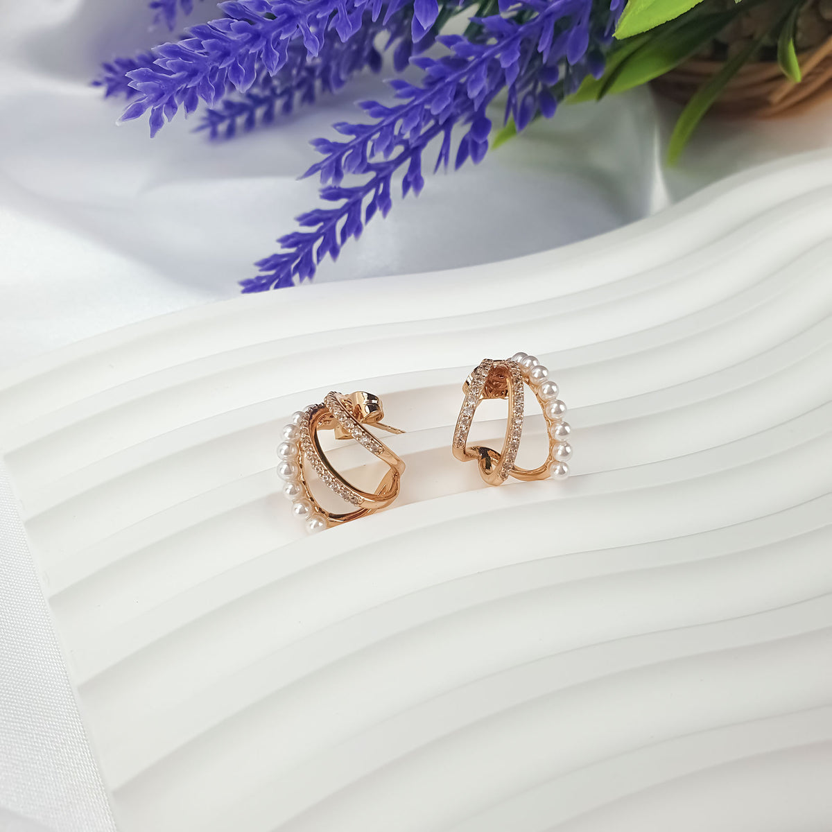 Pair of pearl and cubic zirconia earrings at an angle on white