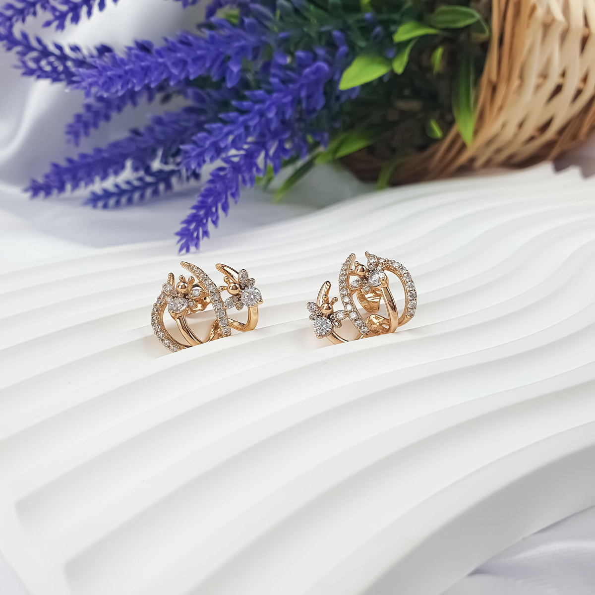 Pair of gold-tone bee earrings with cubic zirconia beside lavender