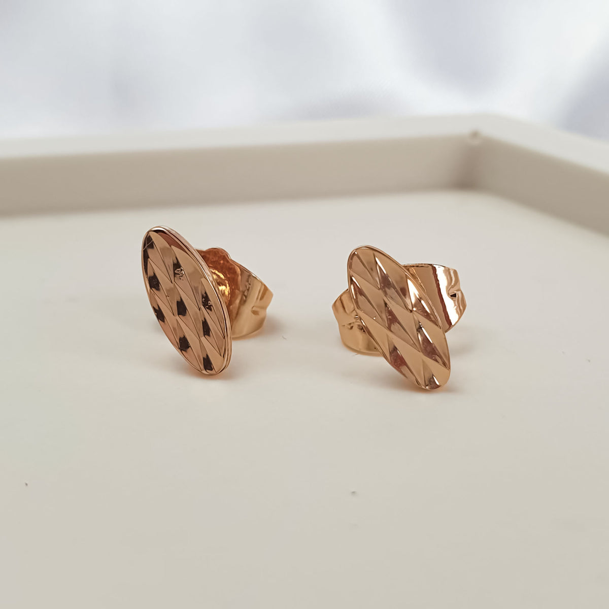 Side view of gold-plated oval earrings showing push-back posts and texture
