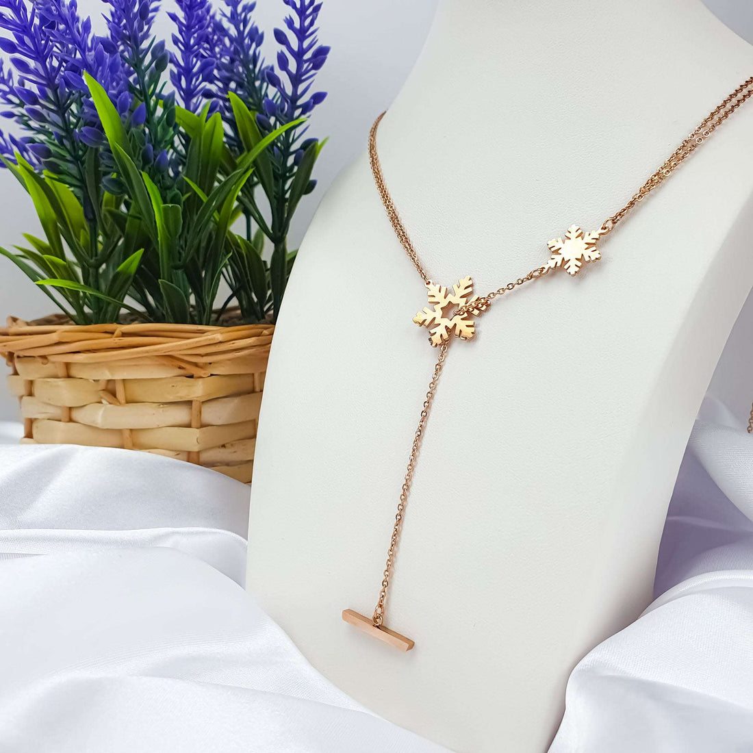 Rose gold-tone snowflake necklace with a long drop on a white display bust