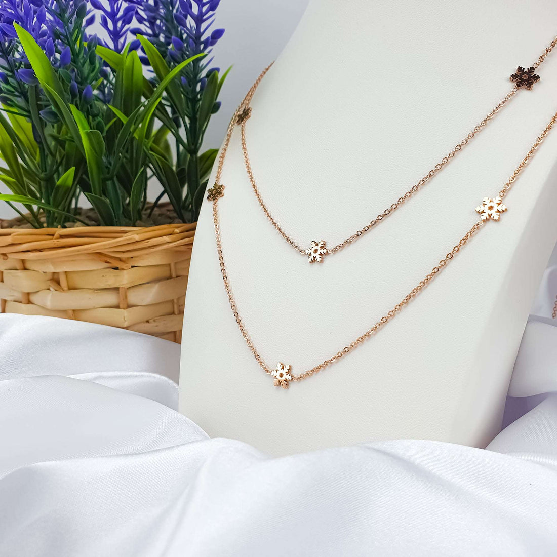Long rose gold-plated necklace with tiny snowflakes on a white display bust